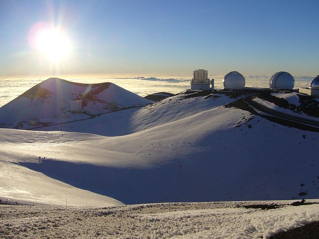 雪景色のマウナケア山頂付近と天体観測所群